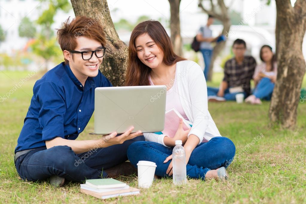 Asian student showing something on laptop