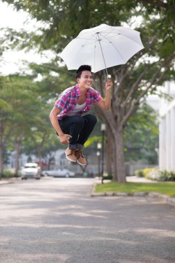 Young man jumping with umbrella clipart