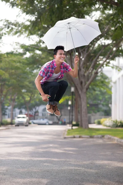 Молодой человек прыгает с зонтиком — стоковое фото