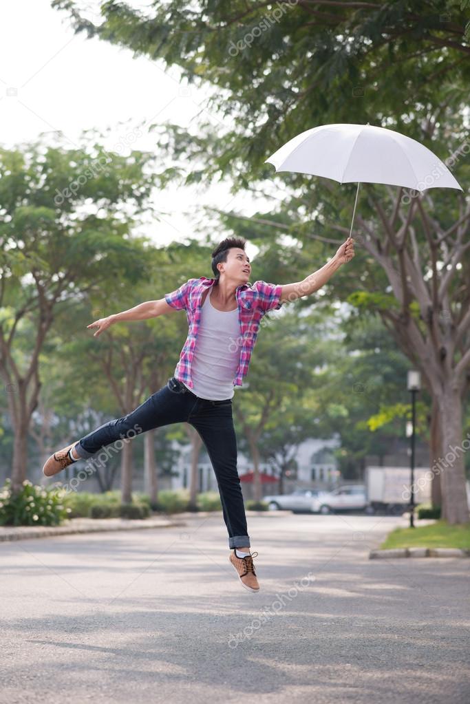 Asian man jumping with umbrella