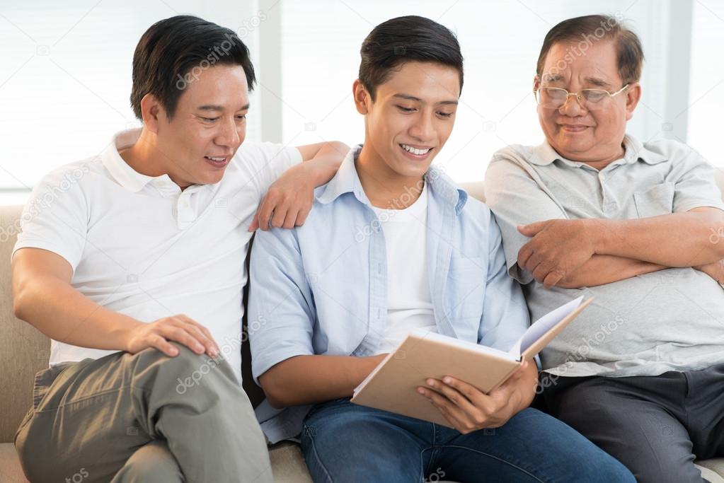 Grandfather, son and grandson reading book