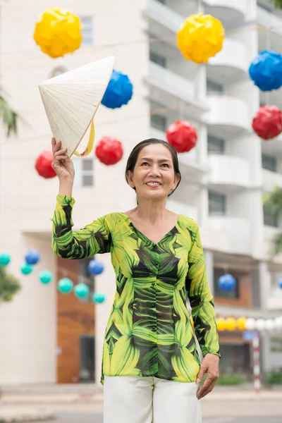 Asian mature woman raising hat — Stock Photo, Image