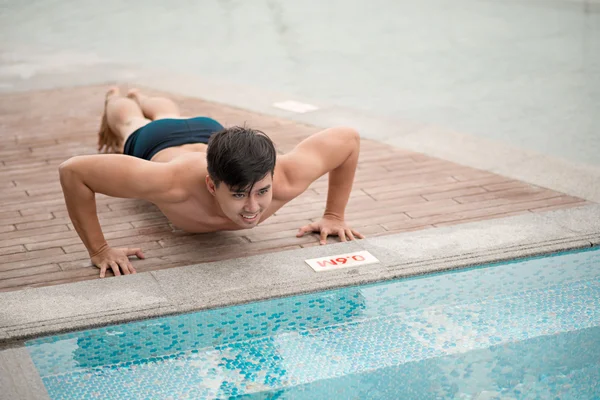 Man doing push-ups by the swimming pool — Stock Photo, Image