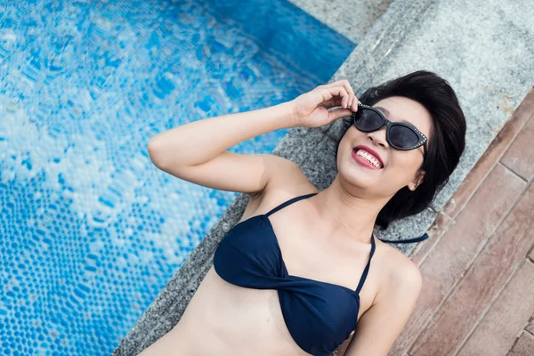 Mujer tomando el sol junto a la piscina — Foto de Stock