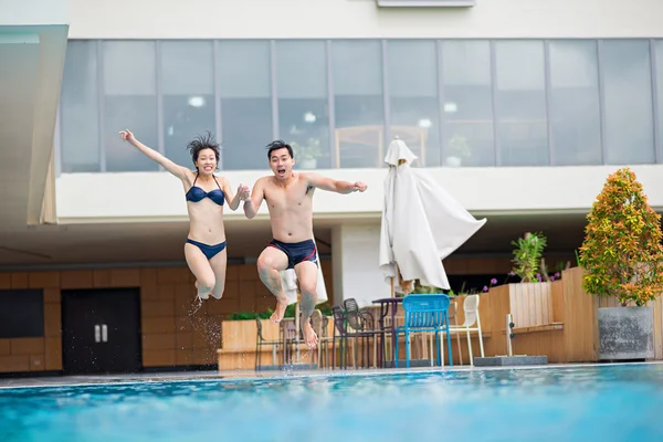 Casal pulando na piscina — Fotografia de Stock