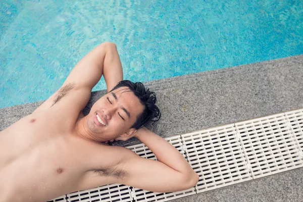 Homem tomando banho de sol na beira da piscina — Fotografia de Stock