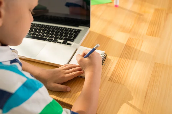 Jongen schrijven iets in zijn Kladblok — Stockfoto