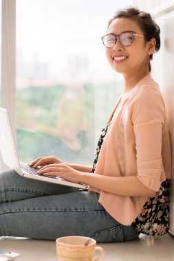 Dizüstü bilgisayarda çalışan genç bir kadın.