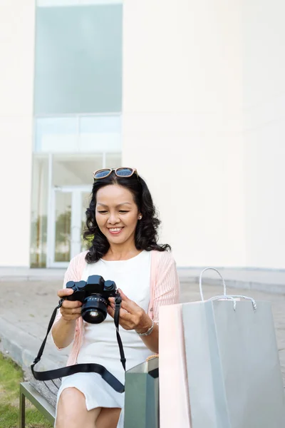 Frau blickt auf ihre Digitalkamera — Stockfoto