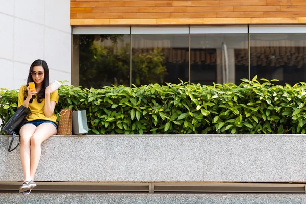 Parapetin üzerinde oturan ve cep telefonu kullanan kız