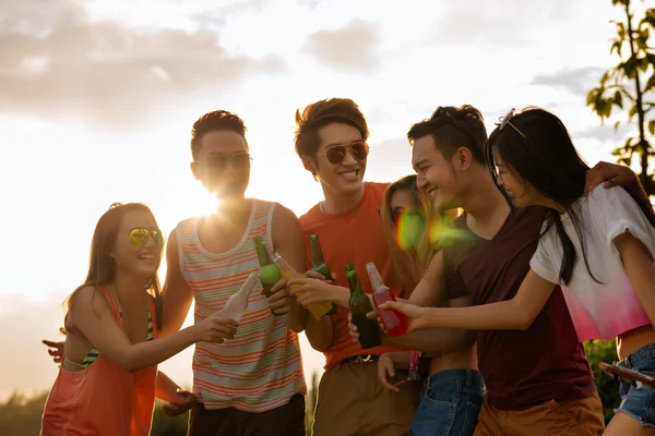 Amici clinking bottiglie alla festa del tramonto — Foto Stock