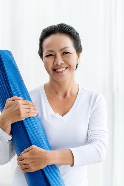 Kvinna med yoga matta leende — Stockfoto