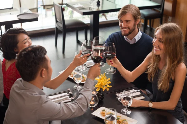 Vrienden rammelende glazen tijdens het diner — Stockfoto