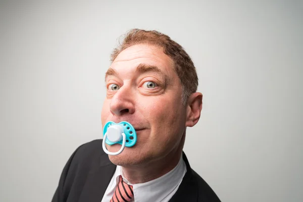 Curious businessman with a pacifier — Stock Photo, Image