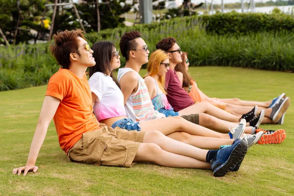 Jonge mensen zittend op het gras — Stockfoto