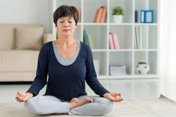 Femme mûre assise en position lotus — Photo