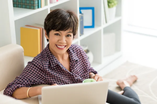 Vrouw met laptop en kopje thee ontspannen — Stockfoto