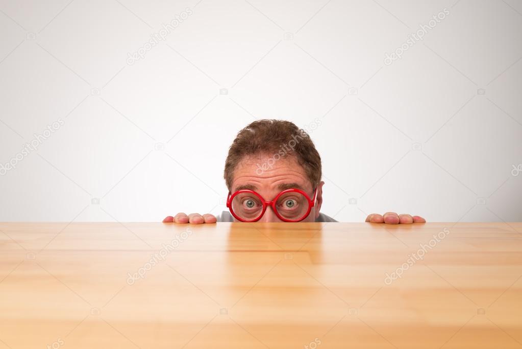 Man in glasses peeking over the table