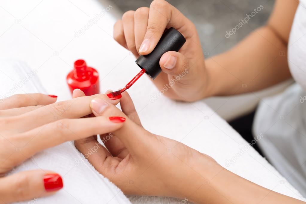 Beautician applying red varnish