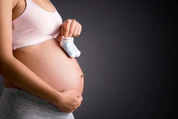 Mulher grávida segurando meias pequenas — Fotografia de Stock