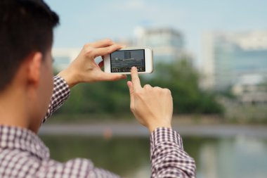 Akıllı telefonla fotoğraf çeken bir adam.