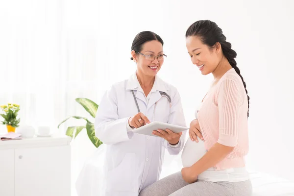 Médecin utilisant un comprimé avec une femme enceinte — Photo
