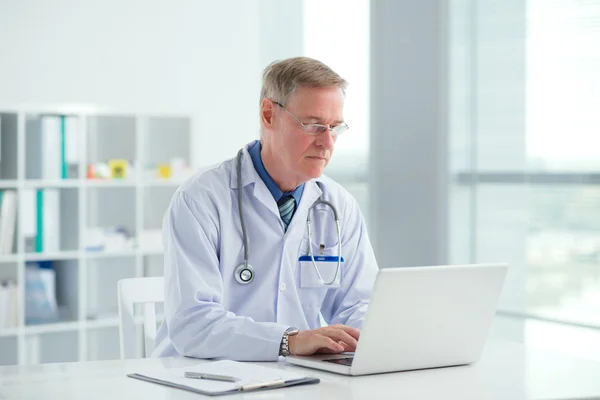 Medico maturo con laptop — Foto Stock