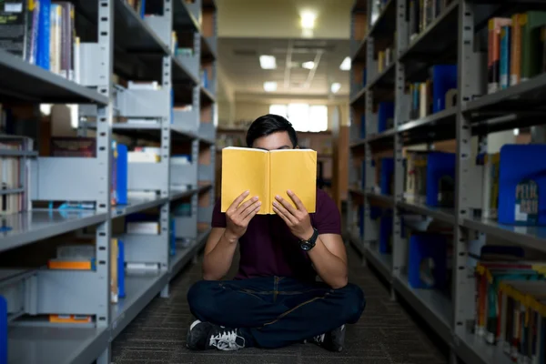 Estudante segurando livro na frente de seu rosto — Fotografia de Stock
