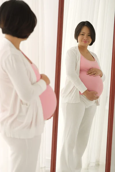Pregnant  woman looking at the mirror — Stock Photo, Image