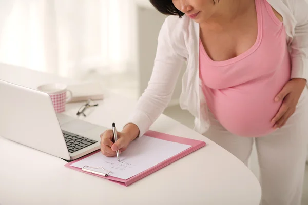 Donna incinta che scrive per fare la lista — Foto Stock