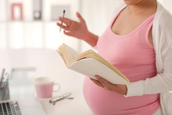 怀孕的女人拿着一本书 — 图库照片
