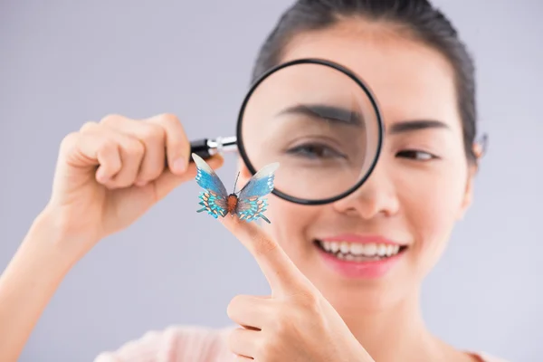 Asian girl with magnifier looking at butterfly — Stock Photo, Image