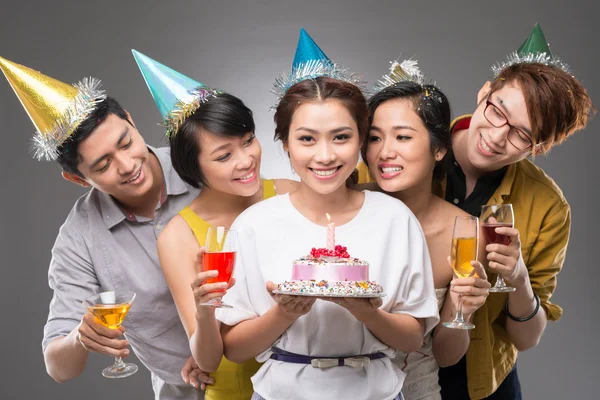 Girl holding a cake with her friends — Stock Photo, Image