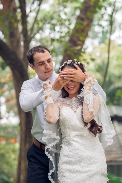 Молодой человек закрывает глаза невесты — стоковое фото