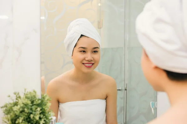 Femme regardant dans le miroir de la salle de bain — Photo