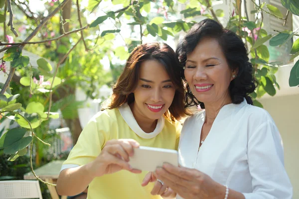 Woman and her daughter using smartphone — Stock Photo, Image