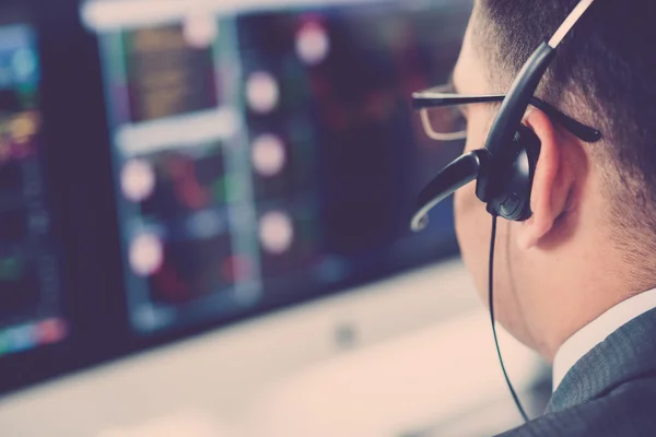 Businessman in headset looking at statistics — Stock Photo, Image