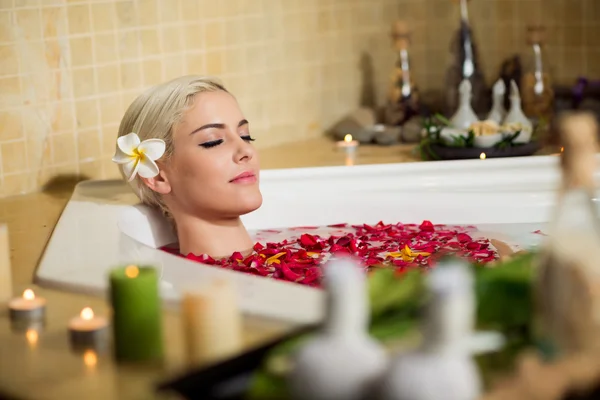 Kvinna att koppla av i badet med kronblad — Stockfoto