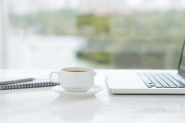 Xícara de café e laptop na mesa — Fotografia de Stock