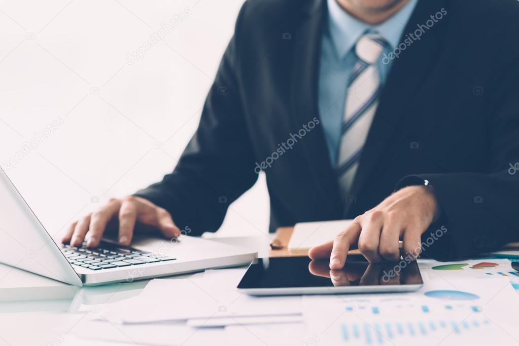Businessman simultaneously using laptop