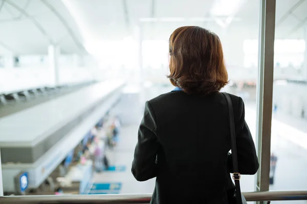 Geschäftsfrau blickt auf Flughafen-Terminal — Stockfoto