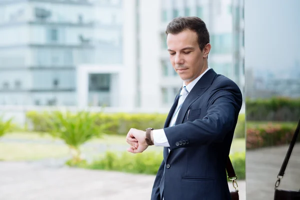 Usmívající se podnikatel při pohledu na hodinky — Stock fotografie