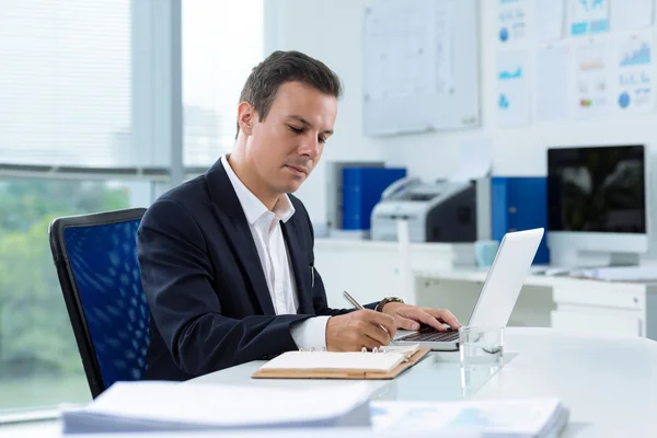 Handsome businessman writing in notepad — Stock Photo, Image