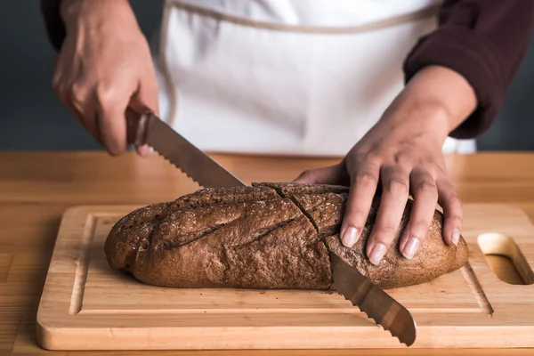 Женщина режет ржаной хлеб — стоковое фото