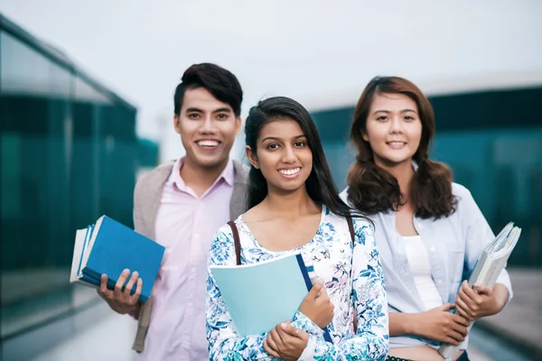 Leende studenter hålla böcker — Stockfoto