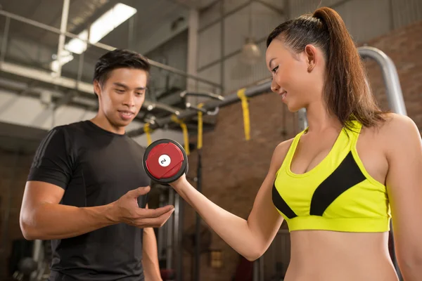 Coach helping woman to choose dumbbell — Stock Photo, Image