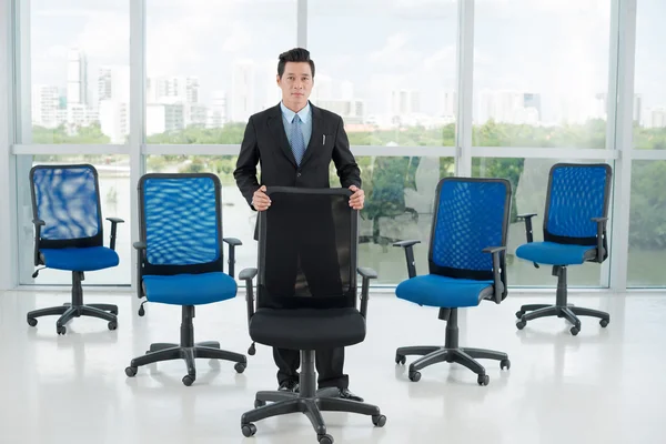 Businessman leaning on empty office chair — Stock Photo, Image