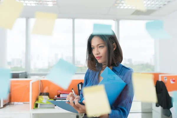 Femme d'affaires regardant des notes adhésives — Photo