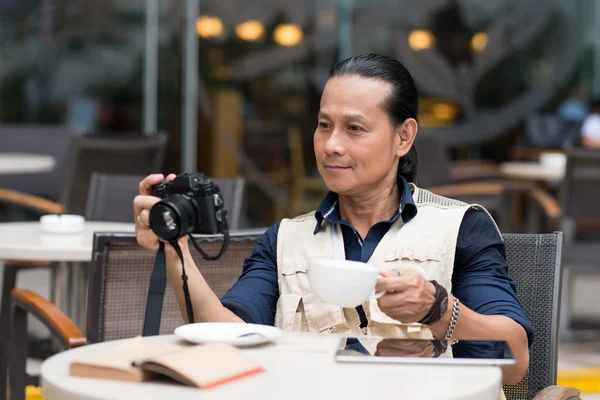 Mann trinkt Kaffee und schaut sich Fotos an — Stockfoto