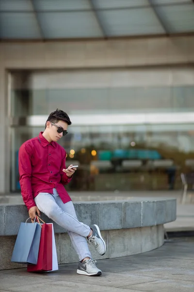 Hombre con bolsas de papel usando smartphone — Foto de Stock